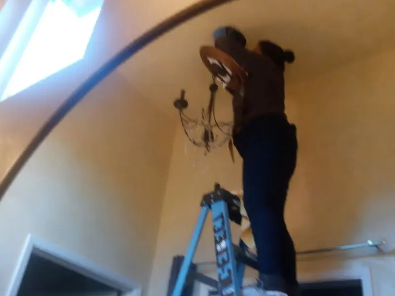 Electrician installing a chandelier in a Mullins residence